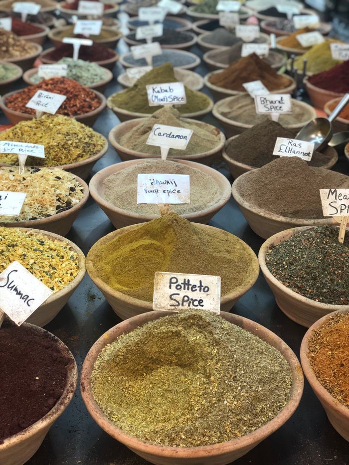 A vibrant assortment of spices displayed in bowls at a market, showcasing diverse flavors and colors.